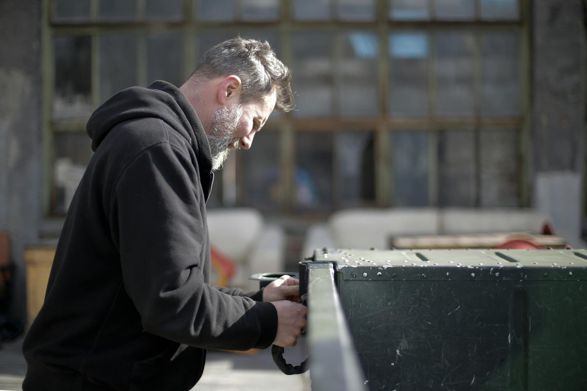 Mechanik w czarnym kombinezonie naprawia samochód przed garażem