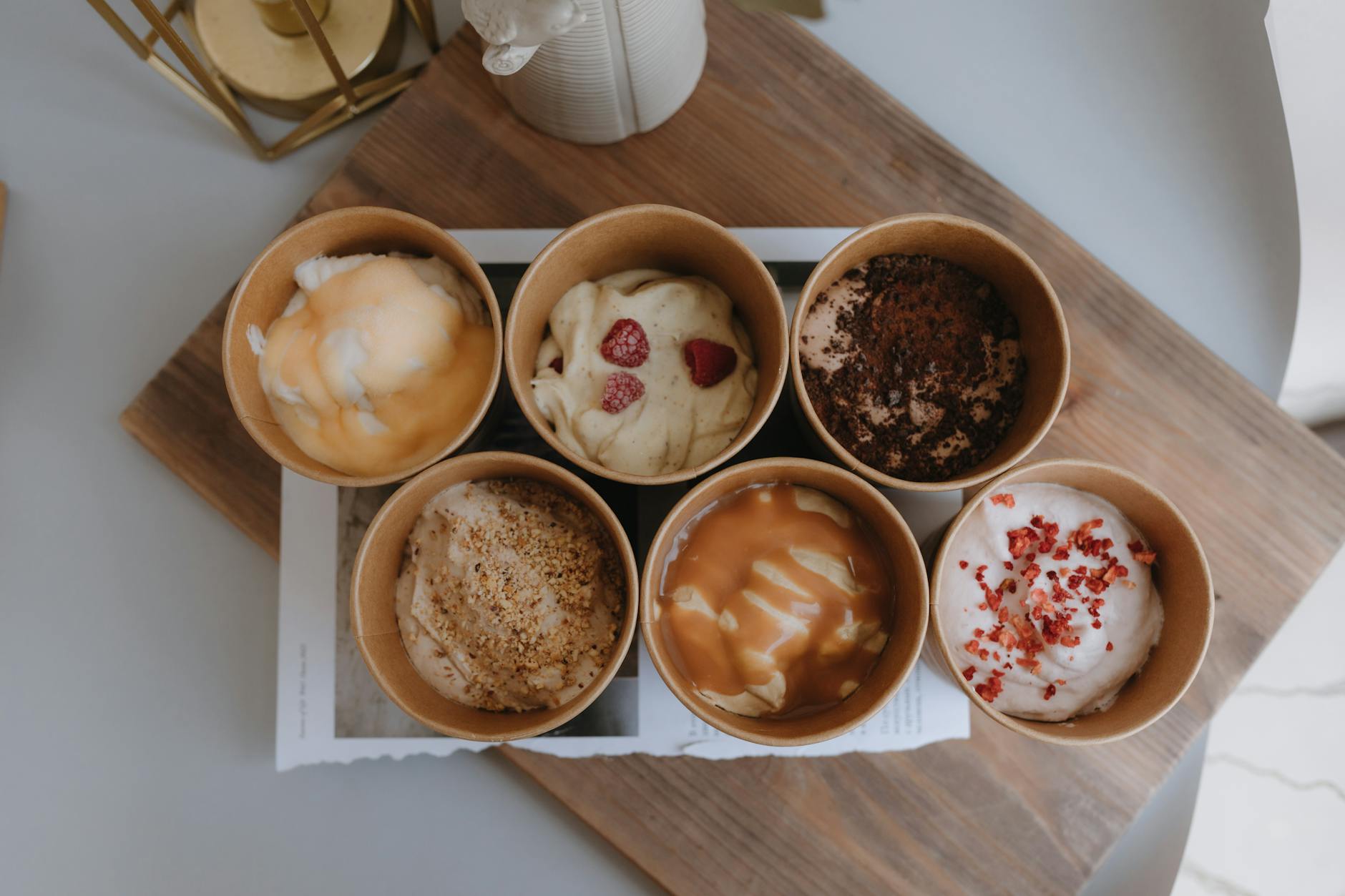 Rzemieślnicze lody w sześciu papierowych kubeczkach na drewnianej tacy