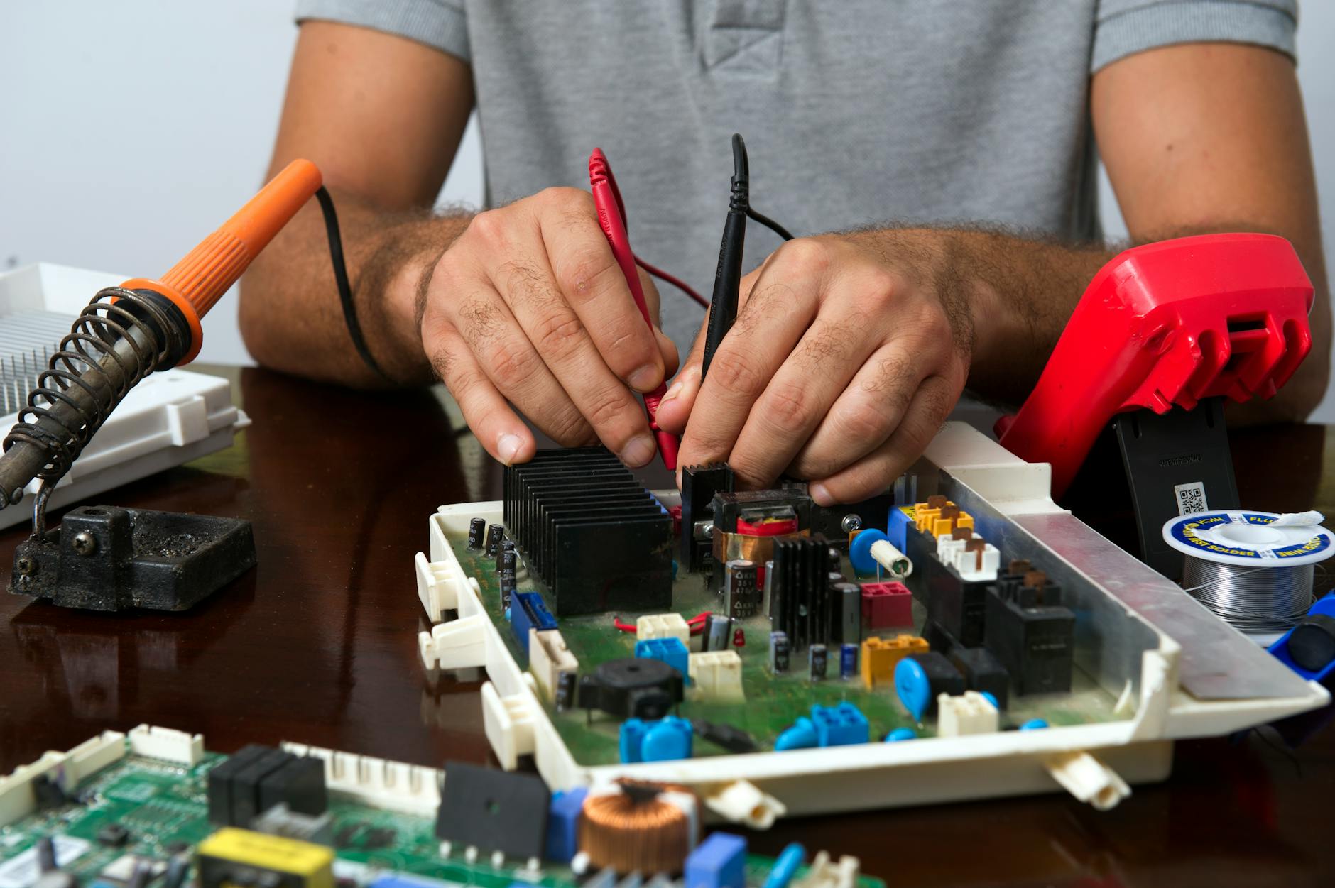 Technik naprawiający płytkę elektroniczną z narzędziami na drewnianym stole