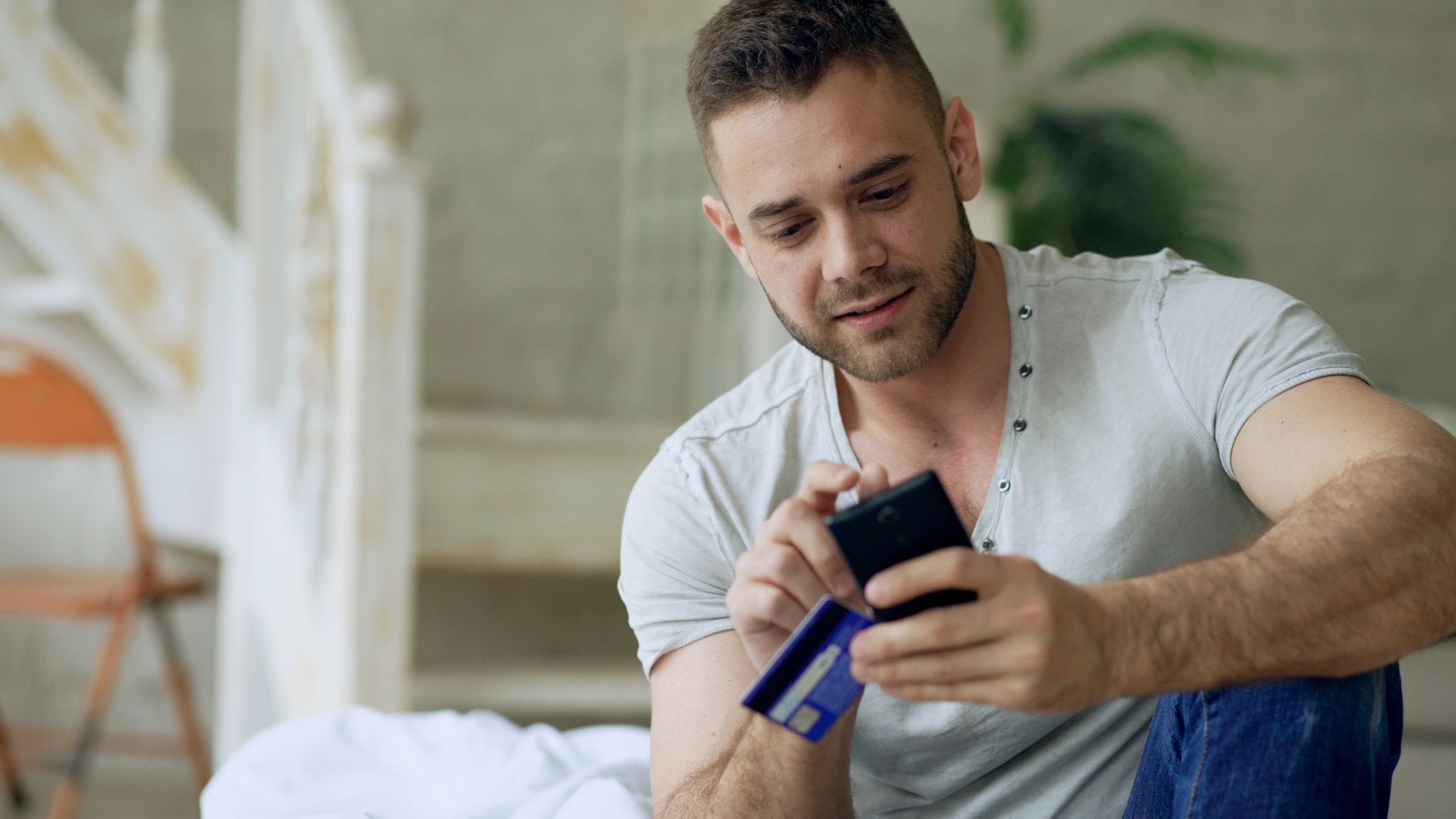 Mężczyzna płaci kartą za zakup auta online na smartfonie