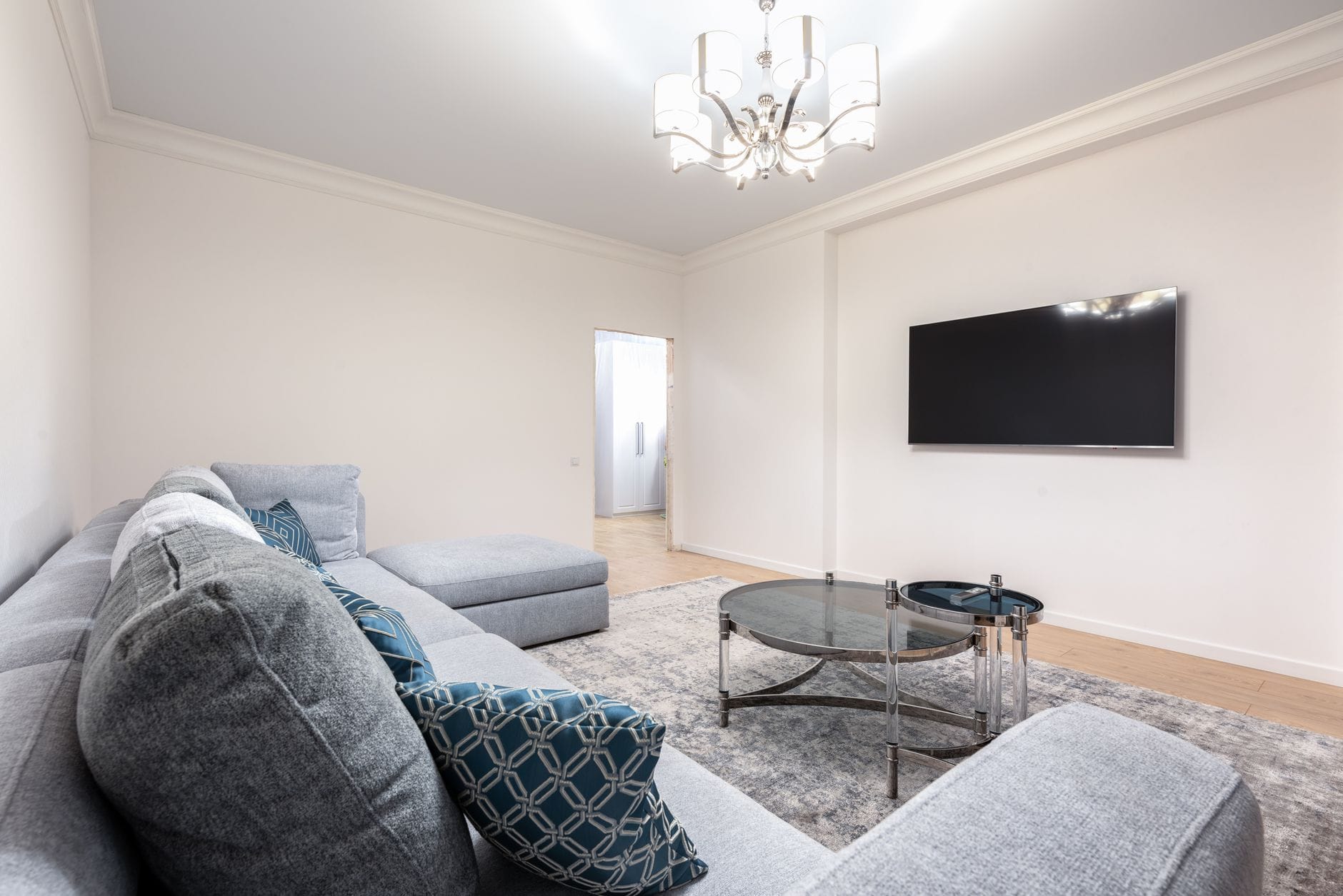 Nowoczesny salon z kanapą, telewizorem i żyrandolem nad stolikiem